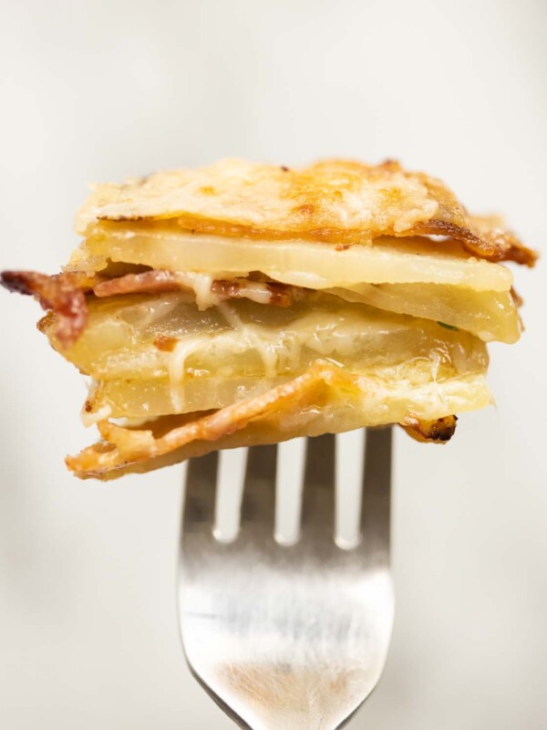 close up shot of half a cheese and bacon potato stacks on silver fork