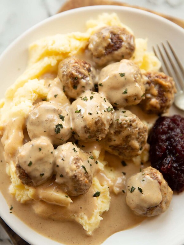 close up shot of Swedish meatballs on mashed potato on small white plate