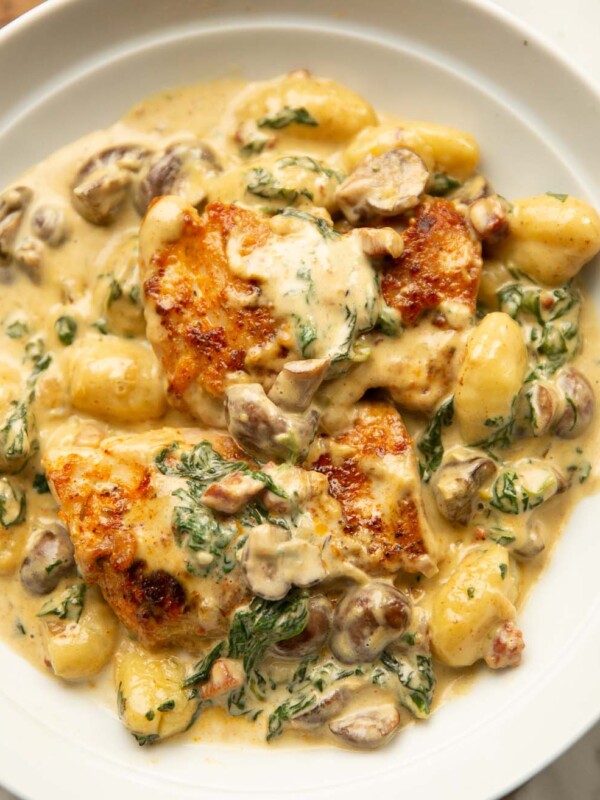 close up shot of creamy chicken with gnocchi in large white bowl