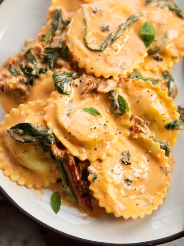 close up shot of creamy tuscan ravioli on small white plate