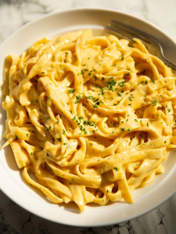 roasted pumpkin alfredo in large white bowl garnished with parsley