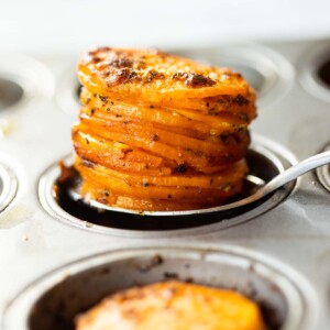 close up shot of silver spoon scooping sweet potato stacks out of muffin tin