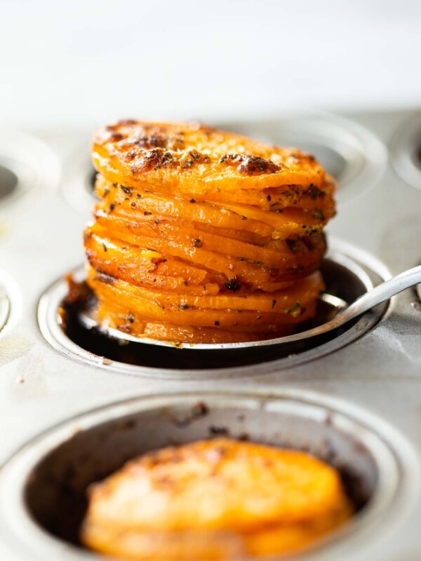 close up shot of silver spoon scooping sweet potato stacks out of muffin tin