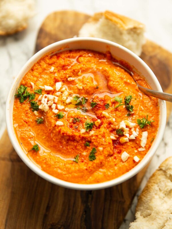 romesco sauce in large white bowl garnished with parsley smoked paprika and almonds