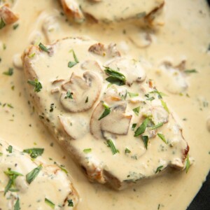 close up overhead shot of pork chop in pan with mushroom sauce