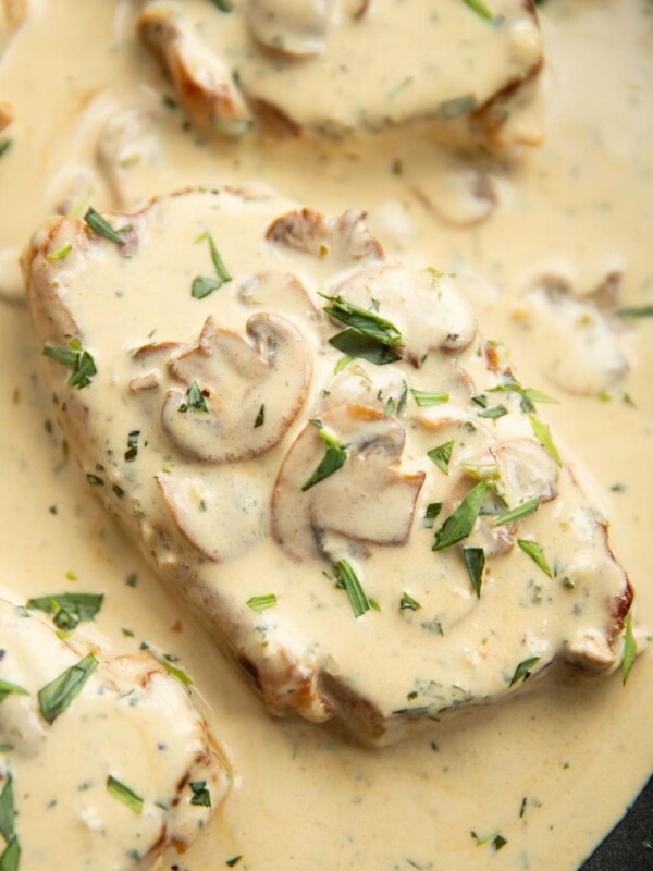 close up overhead shot of pork chop in pan with mushroom sauce