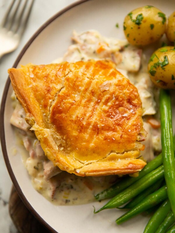 overhead shot of chicken and ham pie served on white plate with potatoes and green beans