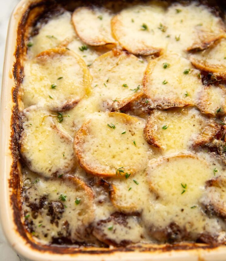 close up shot of french onion potatoes fresh out the oven garnished with fresh thyme