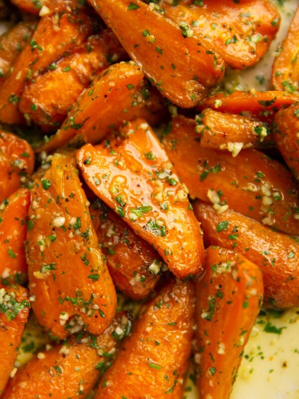 close up shot of garlic roasted carrots in large white baking dish