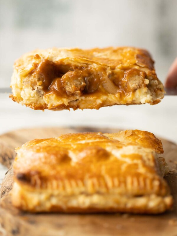 close up shot of knife lifting half a bangers and mash bake showing filling