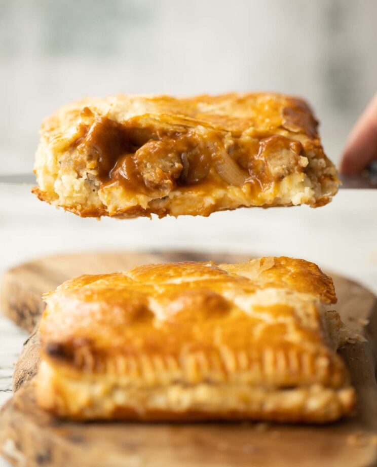 close up shot of knife lifting half a bangers and mash bake showing filling