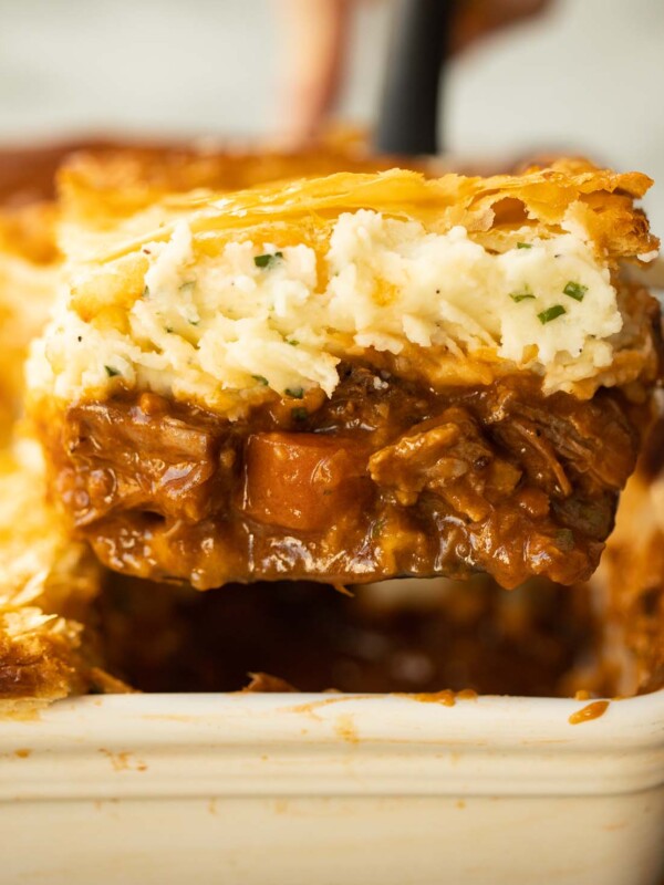 close up shot of spatula lifting portion of steak and guinness pie from baking dish