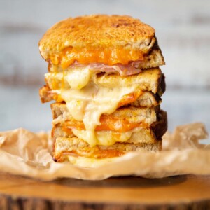 4 toastie halves stacked on each other with cheese spilling out on wooden board