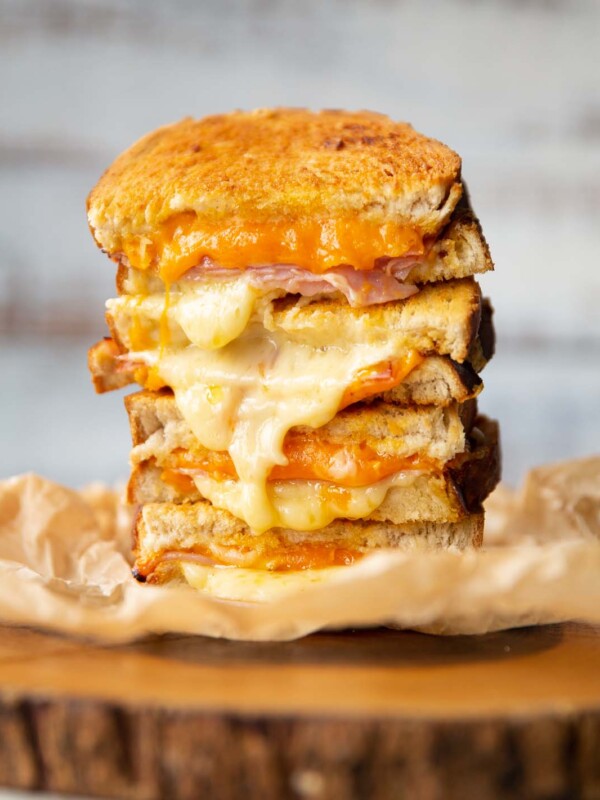 4 toastie halves stacked on each other with cheese spilling out on wooden board