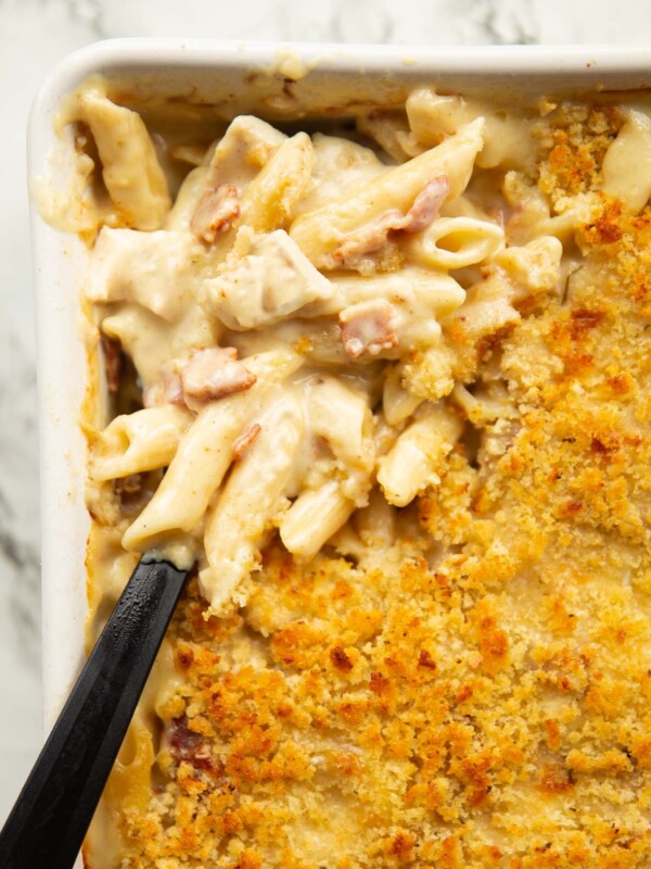 overhead close up shot of chicken bacon pasta bake with black serving spoon digging in