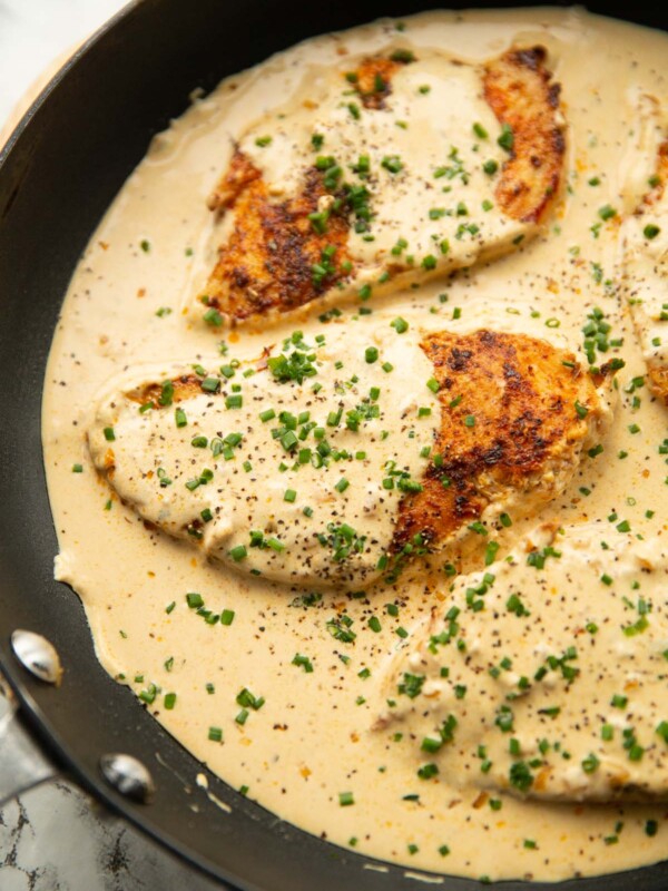 cream cheese chicken in large pan garnished with chives and black pepper