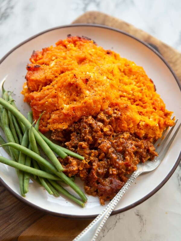 spiced sweet potato shepherds pie served on small white plate with green beans