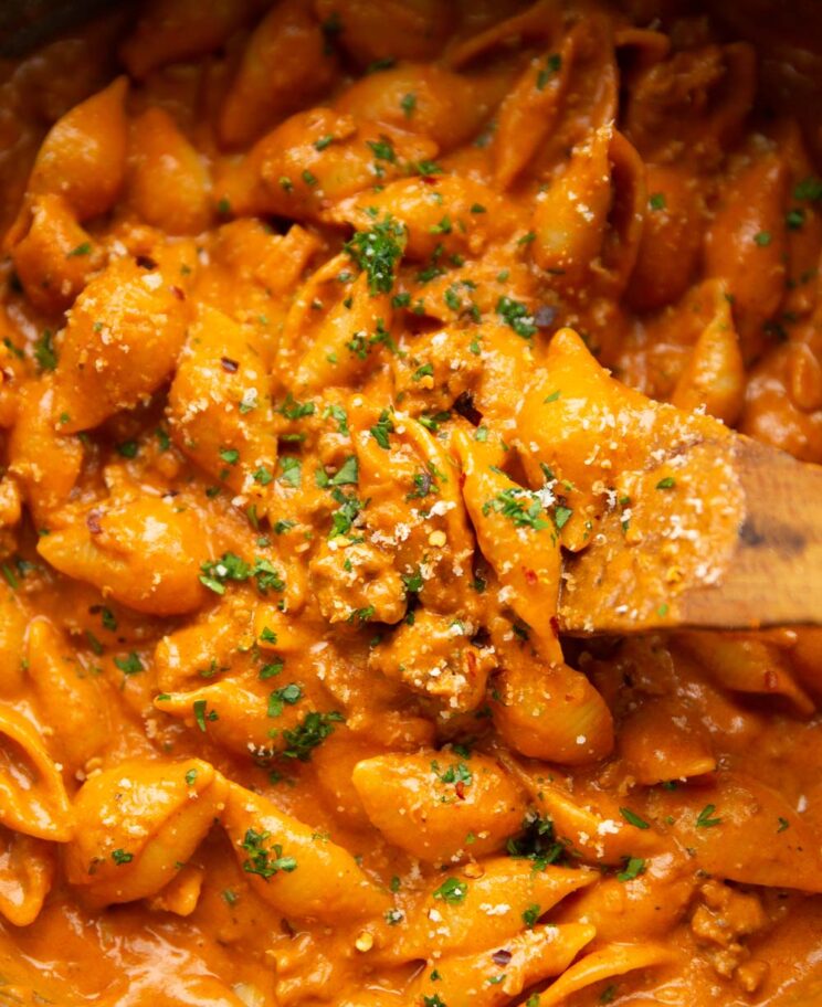 close up shot of wooden spoon in creamy beef pasta in large pot