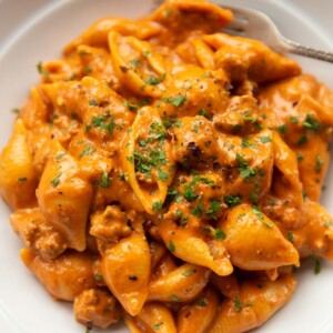 close up shot of creamy beef shells in large white dish with silver fork