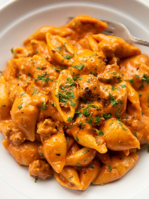 close up shot of creamy beef shells in large white dish with silver fork