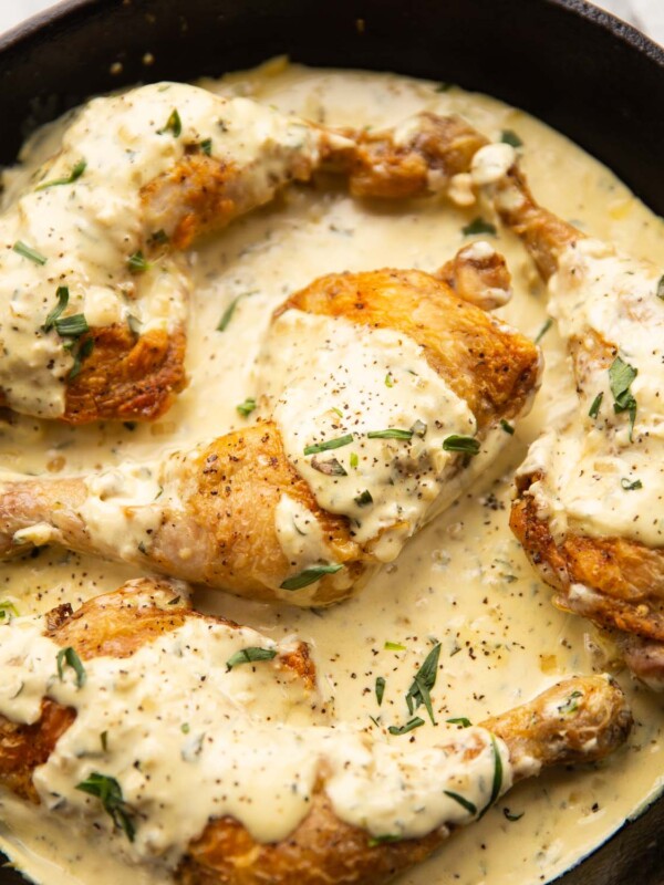 creamy mustard chicken served in large cast-iron pan garnished with tarragon