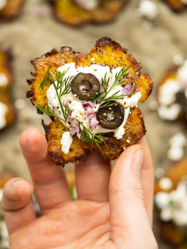 close up overhead shot of hand holding Greek smashed potato