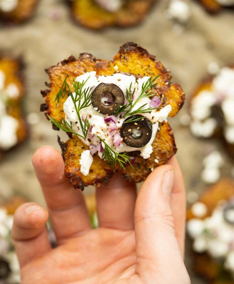 close up overhead shot of hand holding Greek smashed potato