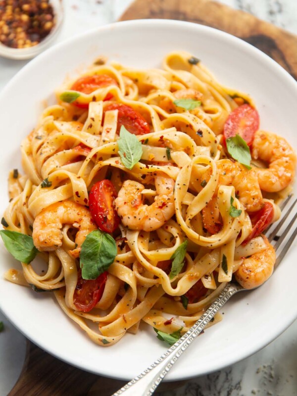 tomato and prawn pasta served on small white plate with silver fork