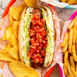 blt hot dog served with tortilla chips in red basket