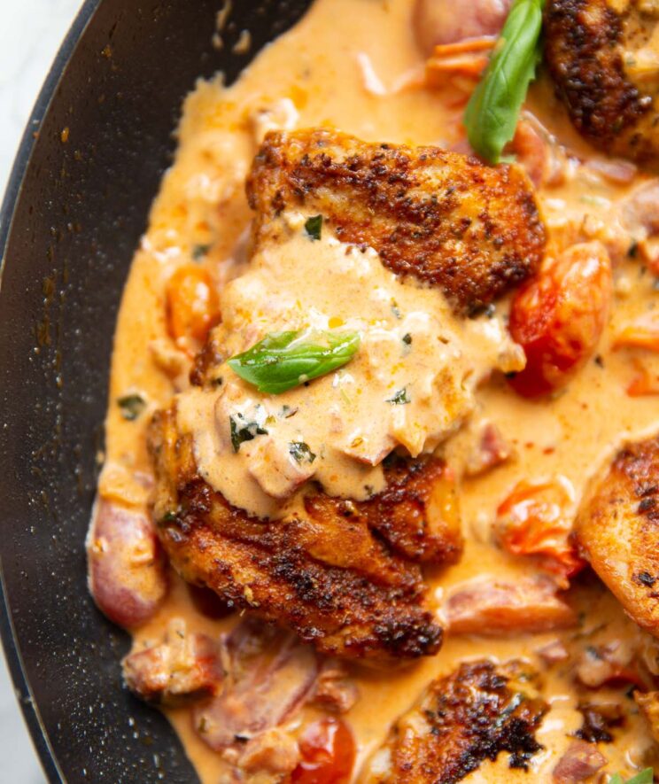 close up overhead shot of chicken thigh in creamy chorizo sauce in large pan