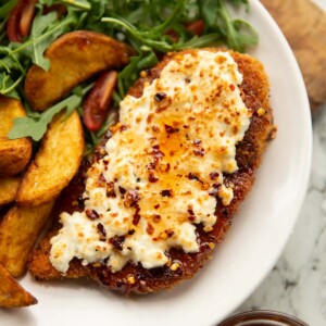 feta hot honey chicken served on small white plate with wedges and rocket