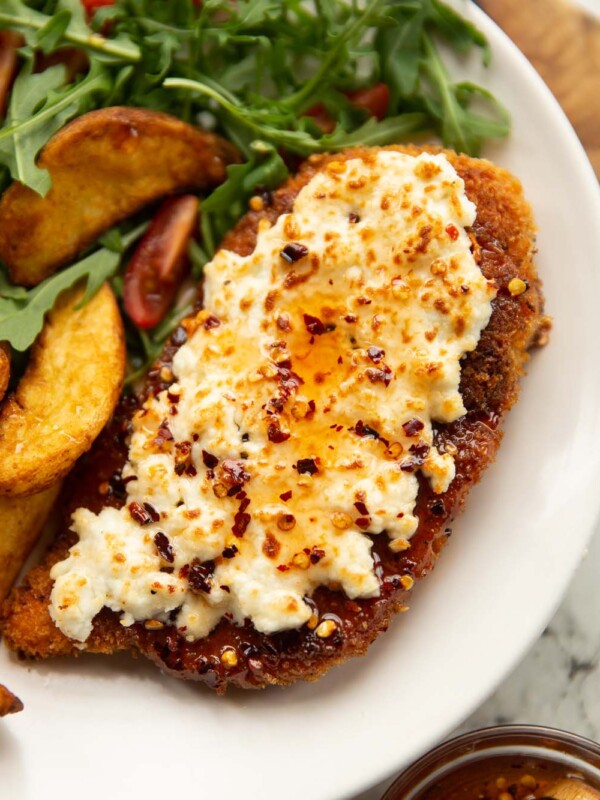 feta hot honey chicken served on small white plate with wedges and rocket