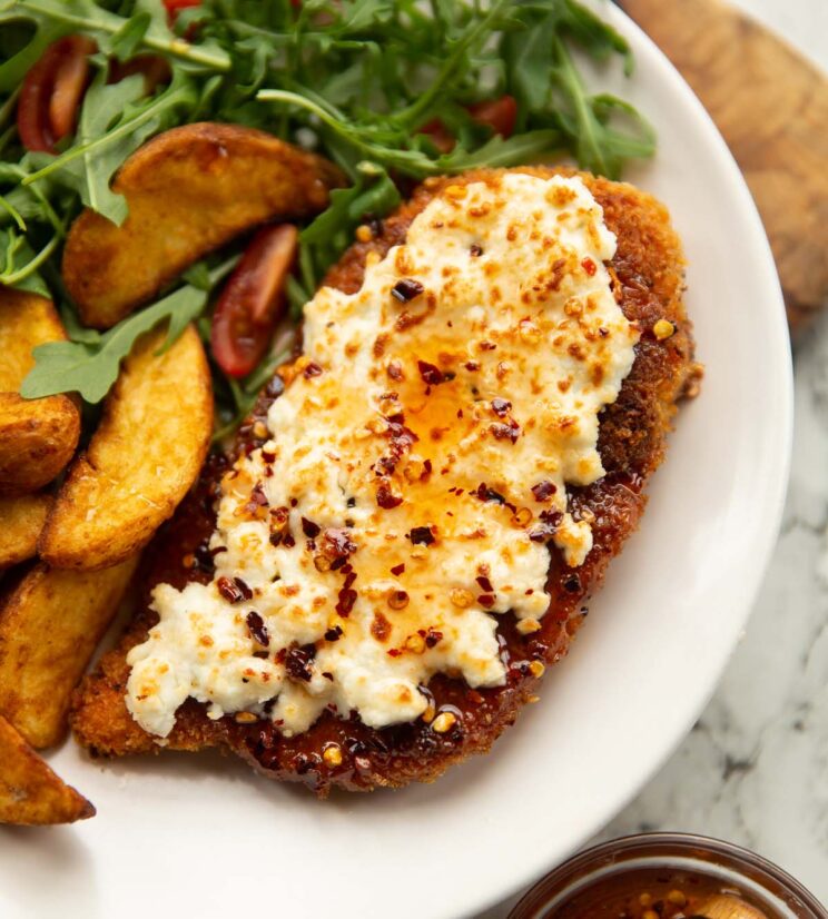 feta hot honey chicken served on small white plate with wedges and rocket