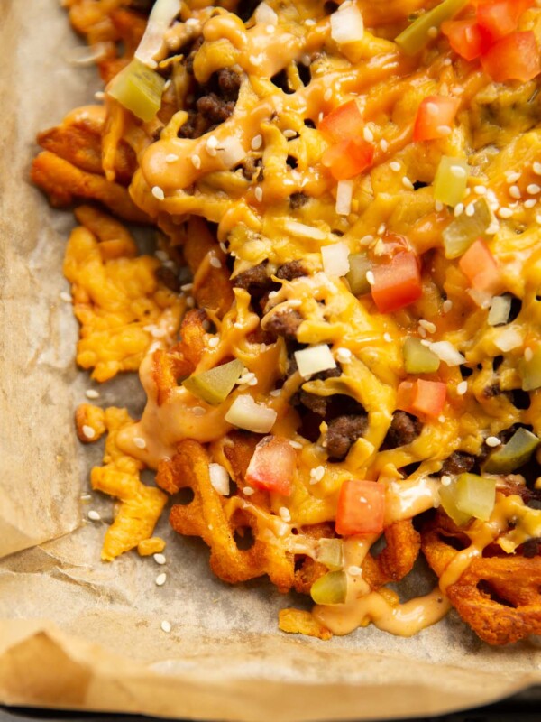 close up shot of loaded cheeseburger waffle fries on baking paper