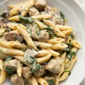 close up shot of sausage and mushroom pasta in large white bowl