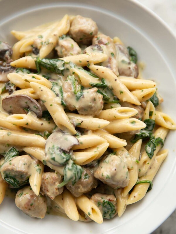 close up shot of sausage and mushroom pasta in large white bowl