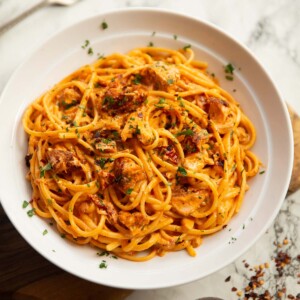 spicy salmon pasta served in large white bowl on marble backdrop