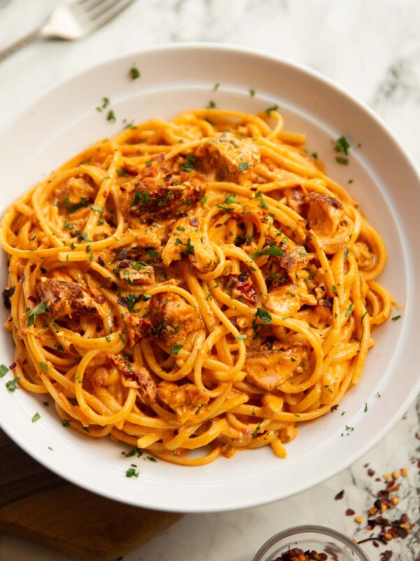 spicy salmon pasta served in large white bowl on marble backdrop