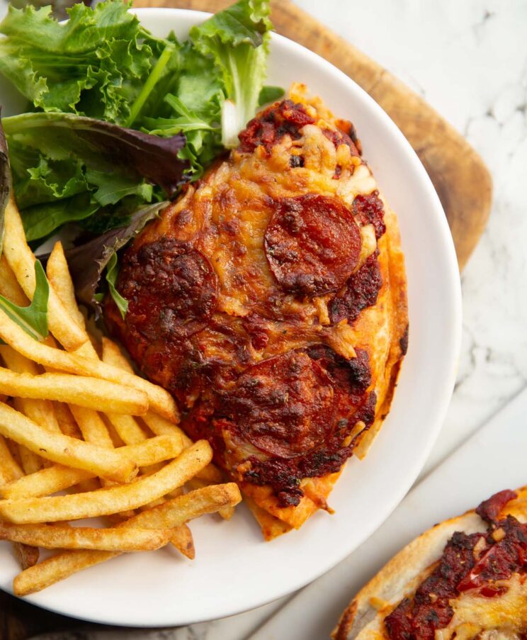 overhead shot of tortilla hack pizza on small white plate with salad and fries