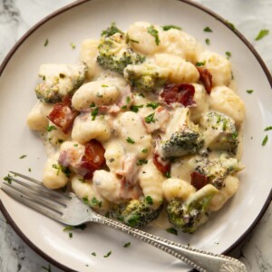 bacon boursin broccoli gnocchi on small white plate with silver fork