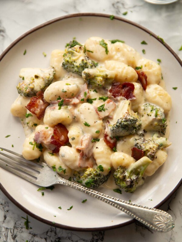 bacon boursin broccoli gnocchi on small white plate with silver fork