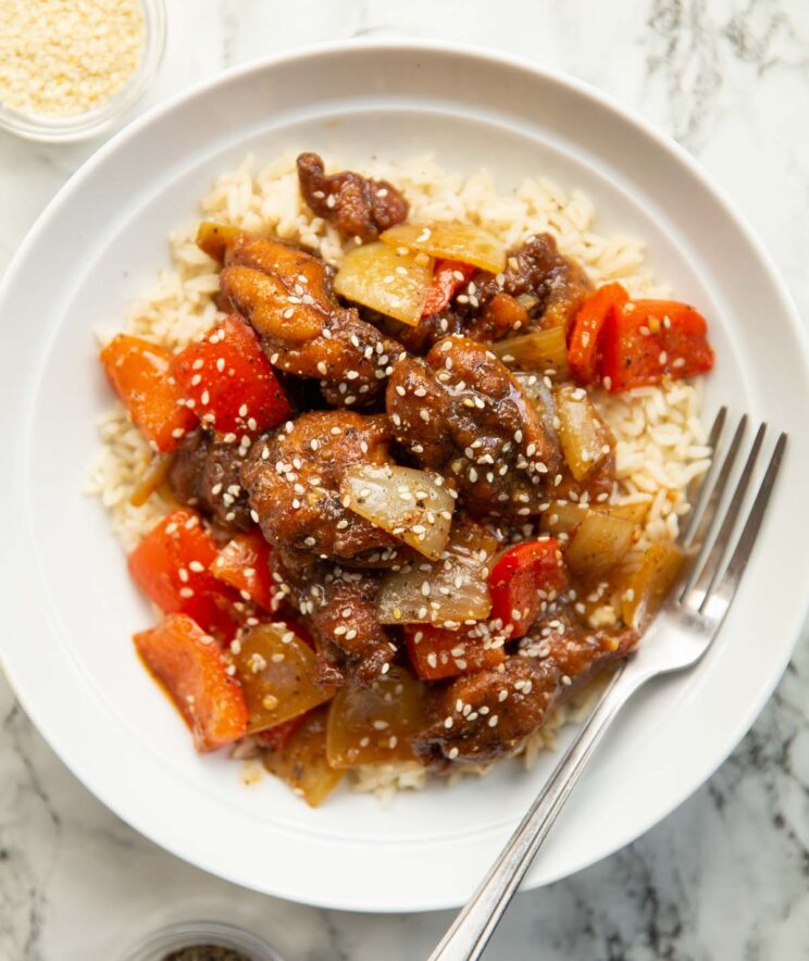 overhead shot of black pepper chicken in large white bowl with silver fork