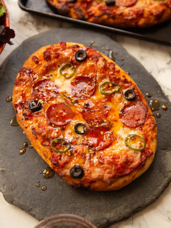 garlic flatbread pizza on slate drizzled with hot honey