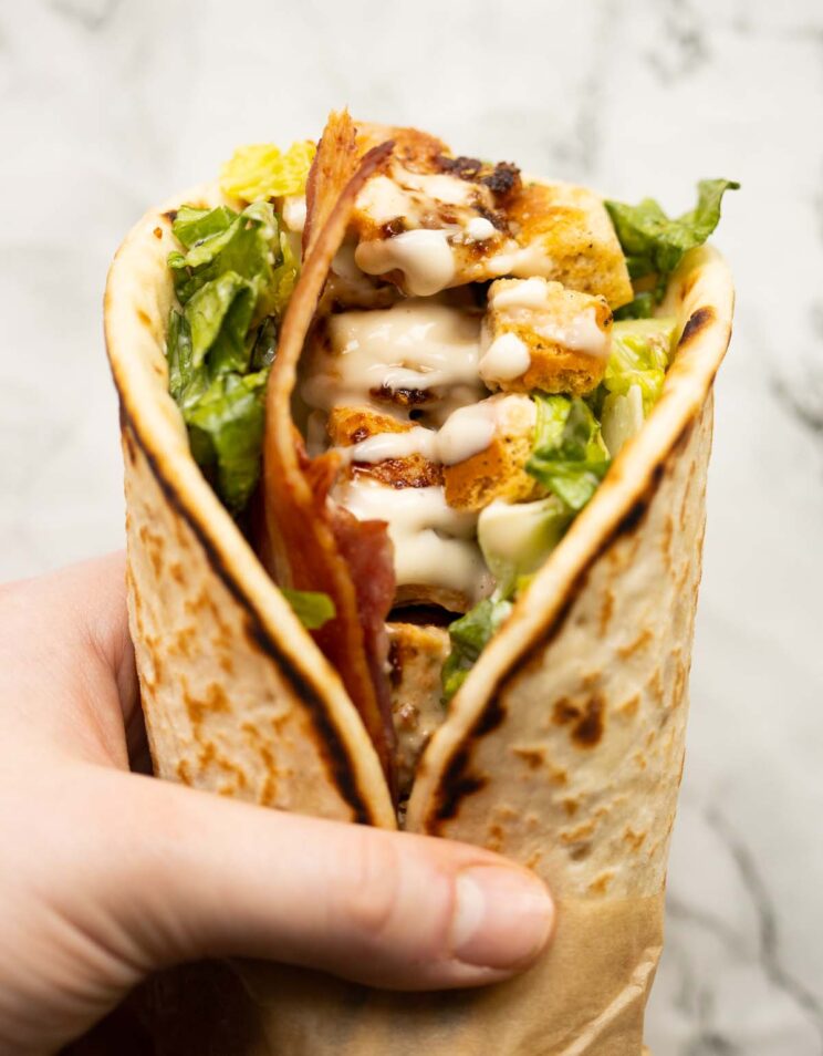 close up overhead shot of hand holding caesar chicken flatbreads