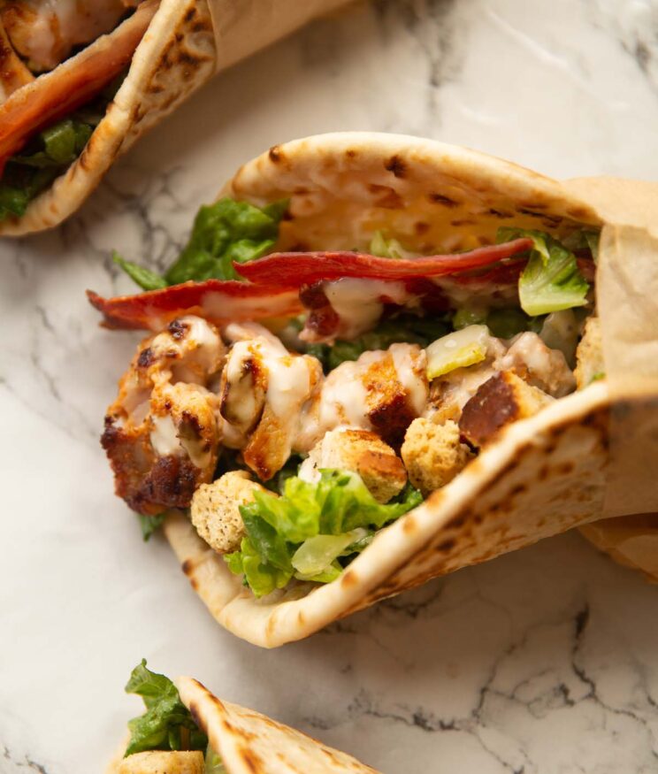 close up shot of chicken caesar flatbread on marble backdrop