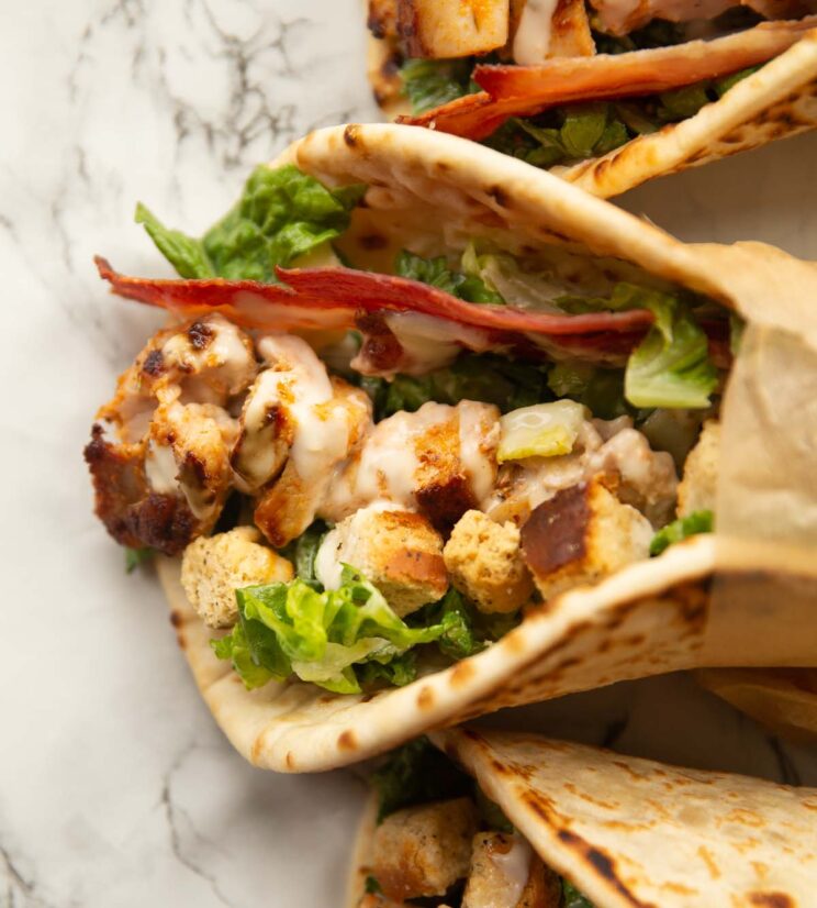 overhead close up shot of chicken caesar flatbread on marble backdrop