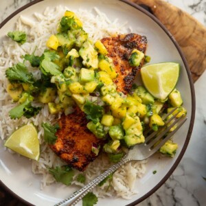 chipotle salmon served with avocado mango salsa on small white plate with rice