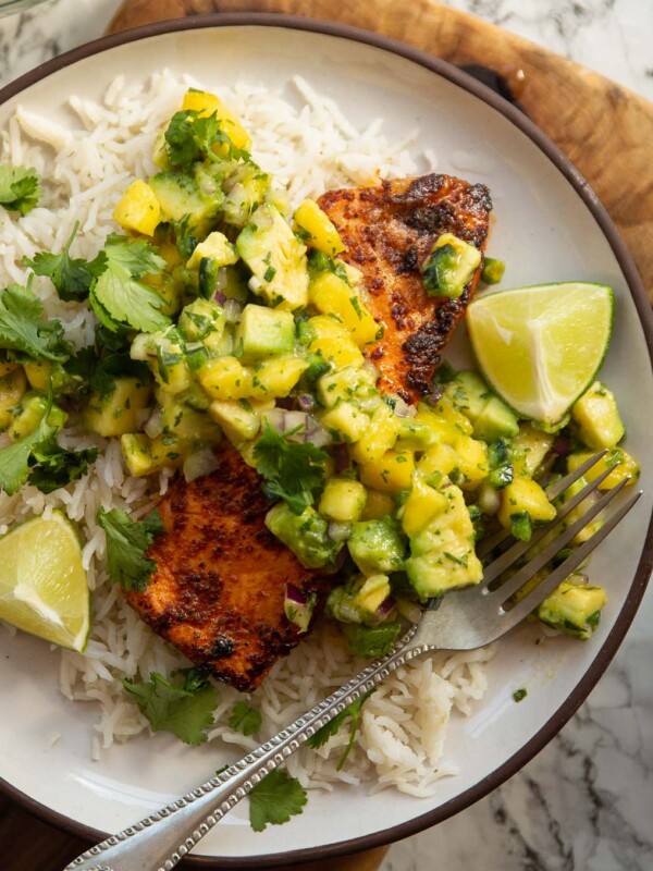 chipotle salmon served with avocado mango salsa on small white plate with rice