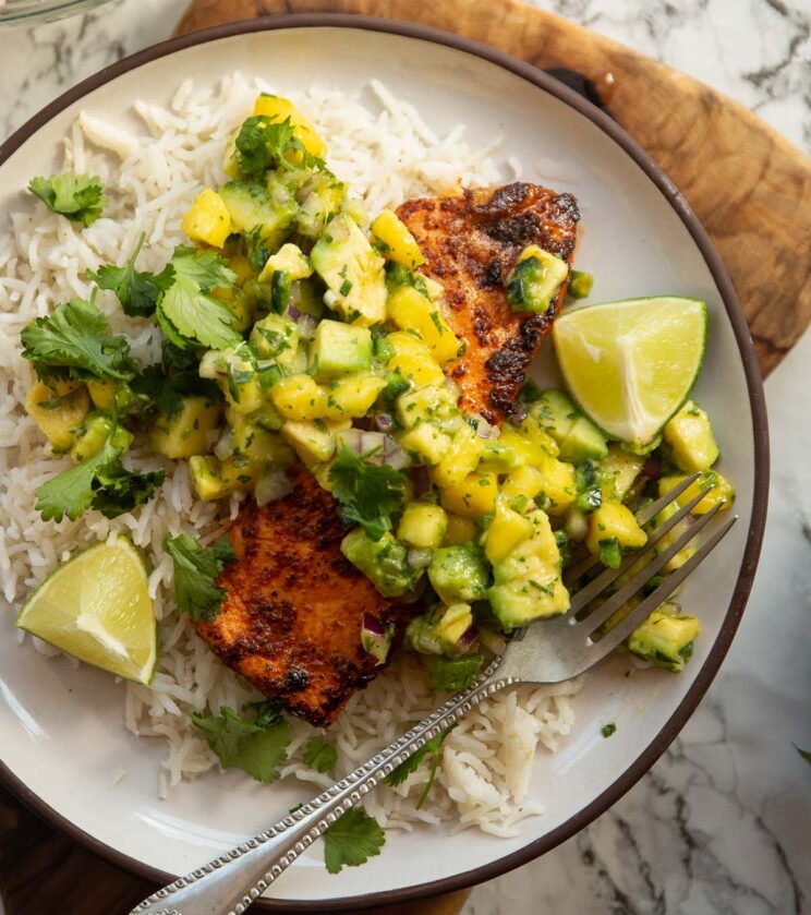 chipotle salmon served with avocado mango salsa on small white plate with rice