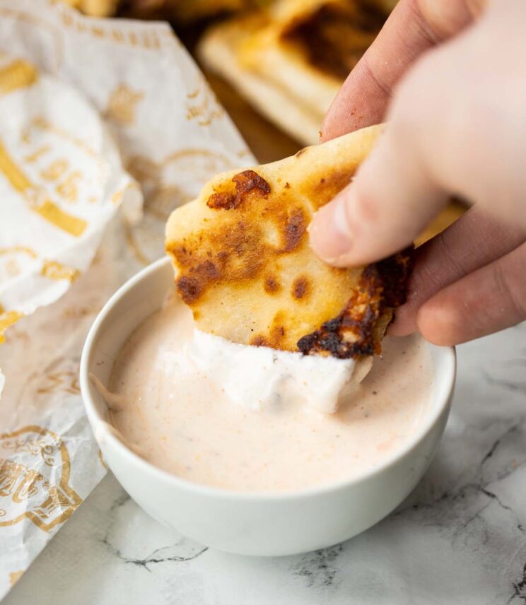 close up shot of hand dunking taco into pot of dip